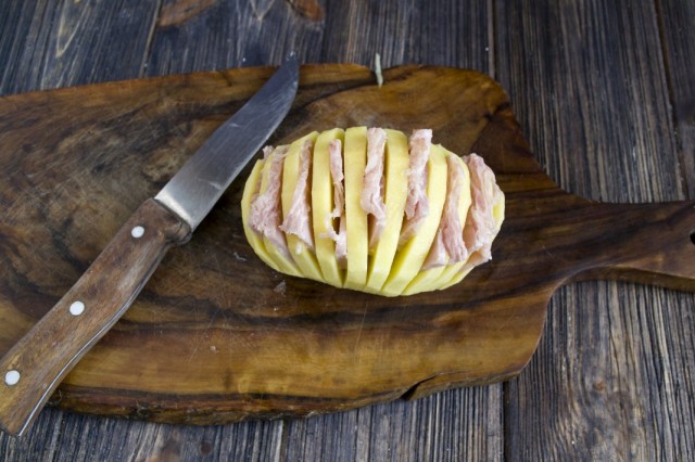 Нарезанную ветчину вставляем в надрезы на картофеле так, чтобы получилась гармошка