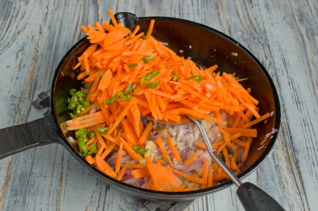 Добавляем в сковороду нашинкованную морковь и нарезанный острый зелёный перец