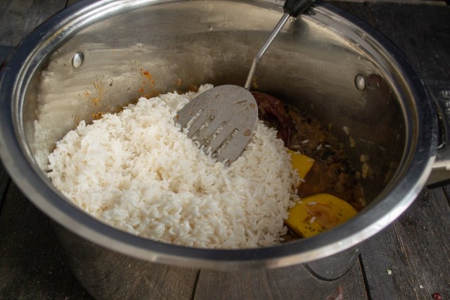 Добавляем рис, головку чеснока и горячую воду