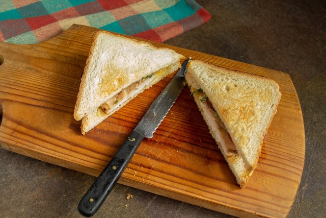 Кладём второй ломтик хлеба и разрезаем по диагонали. Вкусный сэндвич с курицей и помидором готов!