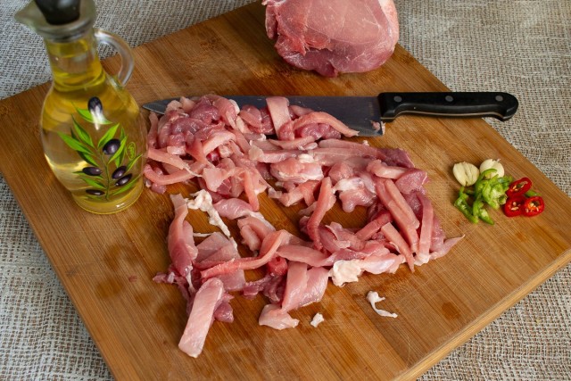 Поливаем нарезанную свинину оливковым маслом, перчим. Добавляем чили и чеснок