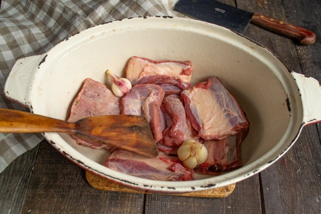 Кладём мясо в жаровню с растительным маслом и добавляем чеснок