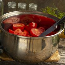 Разрезаем томаты пополам, кладём в кастрюлю с толстым дном, на дно наливаем немного воды