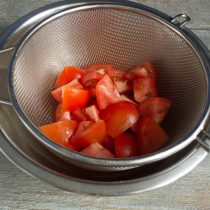 Нарезаем помидоры и кладём в дуршлаг