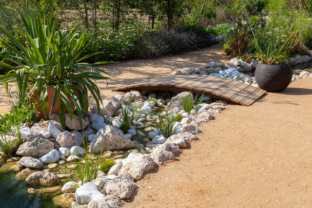 Вариант оформления ручья с помощью камней, растений и мостика