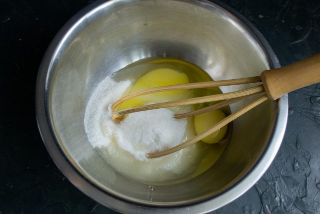 Насыпаем в миску сахарный песок, добавляем соль, куриные яйца и перемешиваем ингредиенты 