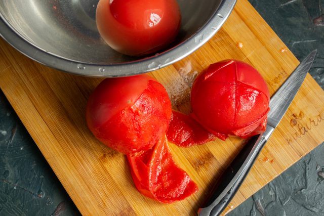 Разрезаем очищенные помидоры, вырезаем плодоножки