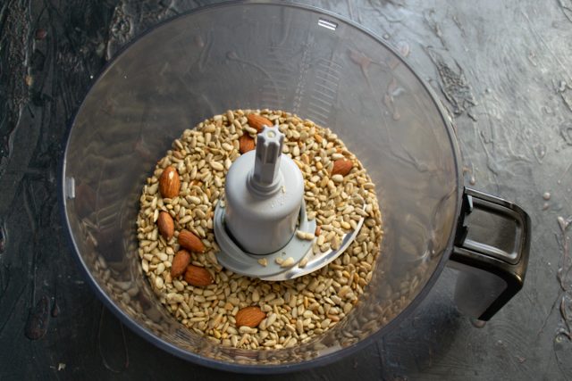 Обжаренные семечки и орехи пересыпаем в чашу кухонного комбайна