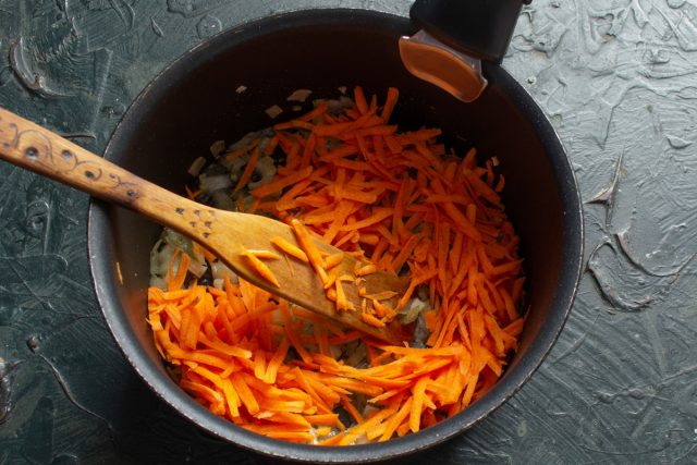 Мелко режем лук и чеснок, кладём в растопленное масло. Морковь натираем на крупной тёрке и кладем к прозрачному луку