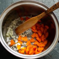 Кладём в кастрюлю нарезанный лук и морковь