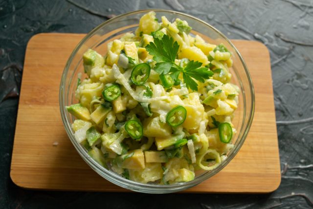Готовый салат с авокадо выкладываем горкой в салатник, украшаем колечками перца чили и листиками петрушки
