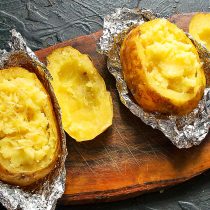 Наполняем картофелины пюре, посыпаем тертым сыром. Кладём фаршированные картофелины в формы