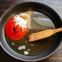 Тем временем делаем томатный соус. Наливаем в глубокую сковороду холодный куриный бульон. Насыпаем крахмал