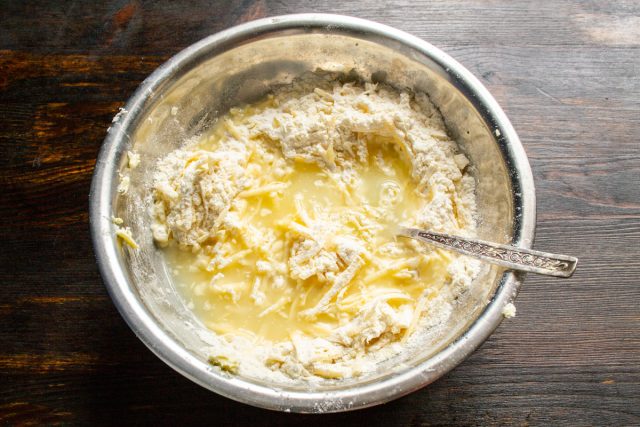 Перетираем сыр с мукой и маслом, чтобы образовались крошки. Вливаем сыворотку.