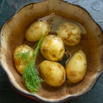 Подготовленный картофель заливаем горячей водой, добавляем веточку укропа.
