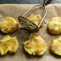 Картофельной толкушкой аккуратно давим картофелины.