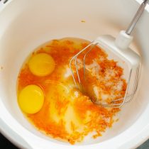Разбиваем куриные яйца. Добавляем тёртую цедру апельсина