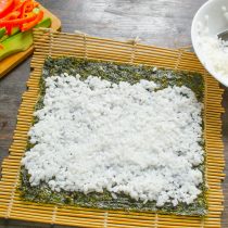 На водоросли выкладываем примерно 2 столовые ложки риса