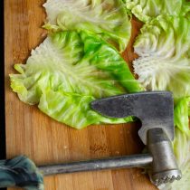 Остужаем капустные листья на доске, молоточком для мяса отбиваем плотную часть. Остужаем капустные листья на доске, молоточком для мяса отбиваем плотную часть.